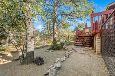 Olgun meşe ağaçları, taş yolu, ahşap güverte merdivenleri, çakıl zemini ve doğal zemini olan tenha bir arka bahçe.