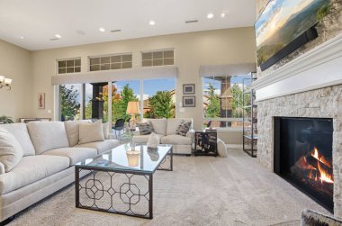 Şöminenin üstünde şöminesi ve sanatı olan rahat bir oturma odası, dekorlu bölüm koltuğu ve kahve masası, peluş.