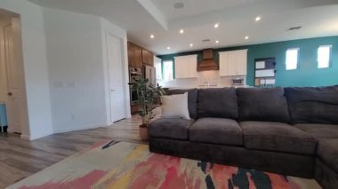 Bölüm kanepeli, renkli halılı ve Teal aksanlı komşu mutfak adalı açık yaşam alanı, aile