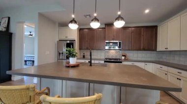 Çağdaş mutfak adası, kolye aydınlatma, geniş tezgah, paslanmaz eşyalar ve ahşap...