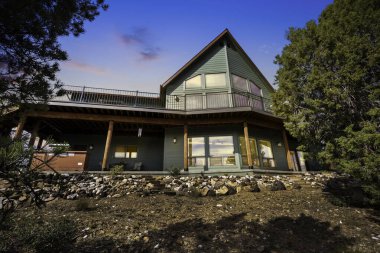 Günbatımında Çağdaş Orman Kulübesi Rocky yamacına tünemiş, Çam Ağaçları, Büyük Üçgen Pencereler,