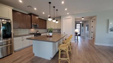 Ada ile Parlak Açık Mutfak, Sarı Tabure, Paslanmaz Aletler, Kolye Işığı, Ahşap Döşeme, Akşam Yemeği