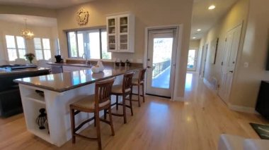 Şömineli ve bitişik mutfak adalı, bar taburesi ve açık yaşam alanı çerçeveli rahat bir salon.,