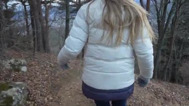 A woman in a white jacket explores a lush forest, capturing tranquil moments as she walks along winding paths and takes in the beauty