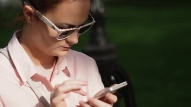 Yaka ve tipik bir haber bir Smartphone Dokunmatik ekranda şık güneş gözlüğü ile şık bir bluz genç kadın