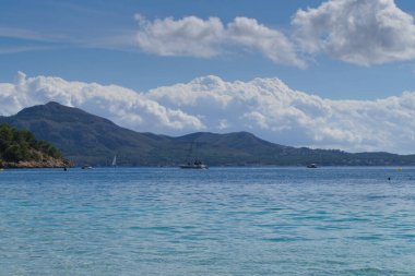Platja de Formentor kıyıları Mallorca 'da bulutlar, botlar ve dağlarla