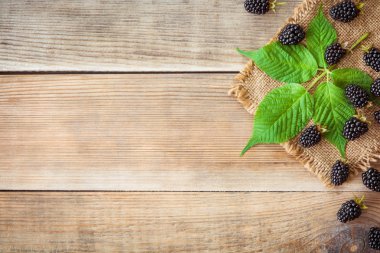 Rustik tarzı ahşap arka plan üzerinde yaprakları ile taze böğürtlen