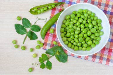 Ahşap arka plan üzerinde beyaz seramik kase taze yeşil bezelye