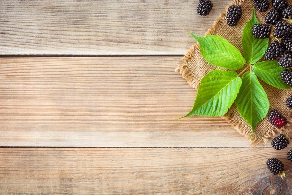 Moras frescas con hojas sobre fondo de madera en estilo rústico — Foto de Stock