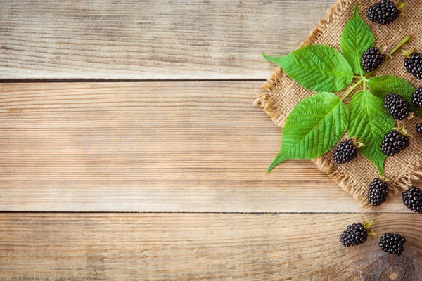 Moras frescas con hojas sobre fondo de madera en estilo rústico — Foto de Stock