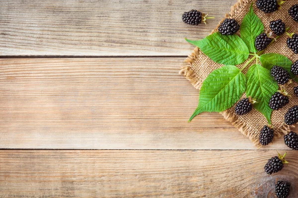 Moras frescas con hojas sobre fondo de madera en estilo rústico — Foto de Stock