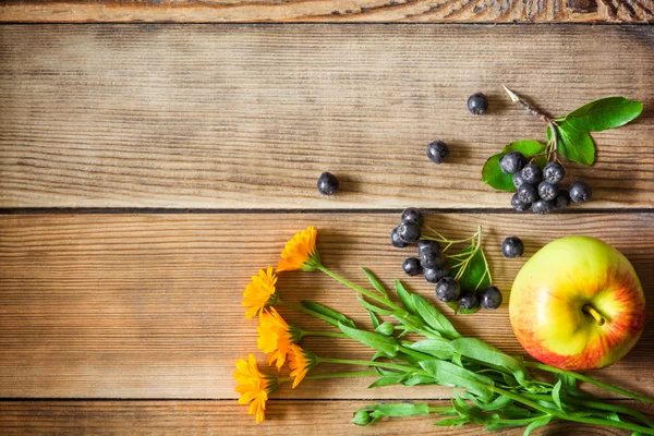 Άνθη καλέντουλας, οι καρποί της αρώνιας (μαύρο chokeberry) και μήλο σε ξύλινα φόντο σε ρουστίκ στυλ — Φωτογραφία Αρχείου