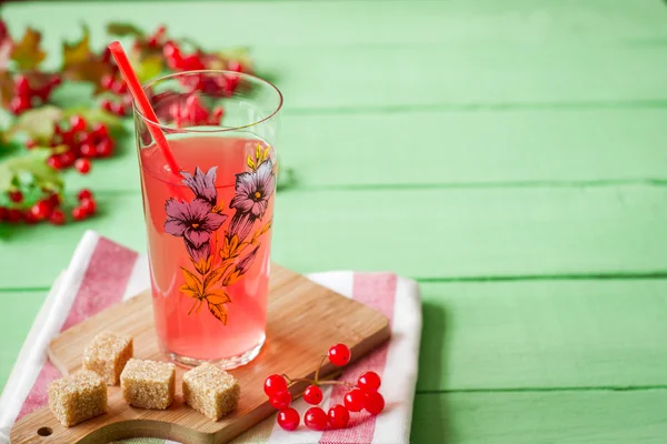 Viburnum frais boisson en verre sur fond de bois vert avec des feuilles et des baies — Photo