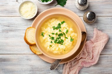 İtalyan stracciatella yumurtalı çorba parmesan peyniri ve sade ahşap arka planda maydanoz. Üst görünüm.