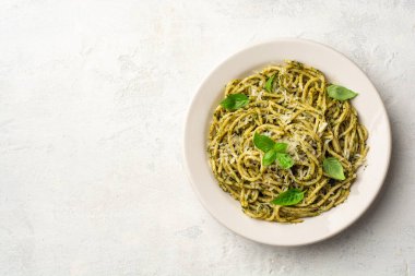 Pesto soslu spagetti makarna, parmesan peyniri ve çimento kaplı fesleğen yaprakları. Üst görünüm, alanı kopyala.
