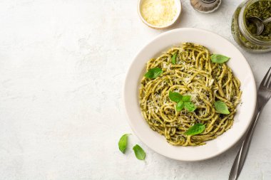 Pesto soslu spagetti makarna, parmesan peyniri ve çimento kaplı fesleğen yaprakları. Üst görünüm, alanı kopyala.