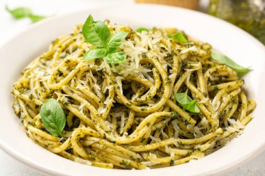 Pesto soslu spagetti makarna, parmesan peyniri ve çimento kaplı fesleğen yaprakları. Seçici odak.