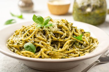 Pesto soslu spagetti makarna, parmesan peyniri ve çimento kaplı fesleğen yaprakları. Seçici odak.