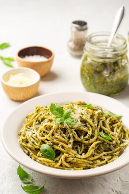 Pesto soslu spagetti makarna, parmesan peyniri ve çimento kaplı fesleğen yaprakları. Seçici odak.
