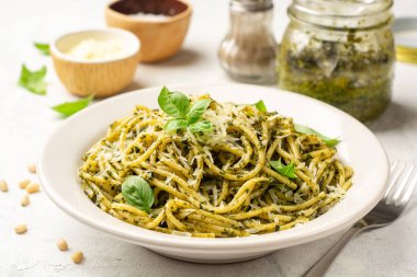 Pesto soslu spagetti makarna, parmesan peyniri ve çimento kaplı fesleğen yaprakları. Seçici odak.