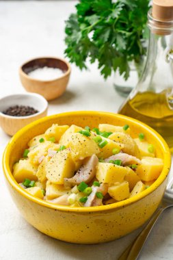 Tuzlu ringa balıklı patates salatası ve çimento arka planda seramik kasede soğan. Seçici odak.