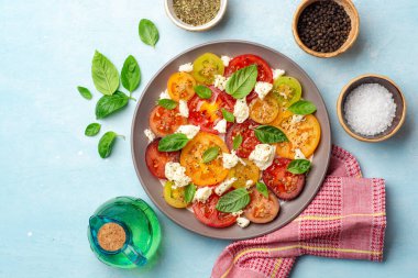 Varisli domatesli İtalyan caprese salatası, mozzarella peyniri, fesleğen yaprağı, baharat ve beton kaplama zeytinyağı. Üst görünüm.