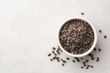 Himalaya ya da gri beton arka planda seramik kasede Hint siyah tuzu. Üst görünüm, alanı kopyala.