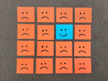 Elle çizilmiş hüzünlü yüz ifadeleri yapışkan notların üzerinde gülümseme emojisinde göze çarpıyor, pozitif yol konsepti.