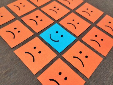 Elle çizilmiş hüzünlü yüz ifadeleri yapışkan notların üzerinde gülümseme emojisinde göze çarpıyor, pozitif yol konsepti.