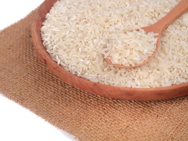 Çuval bezi arka planında tahta bir kasede çiğ beyaz pirinç manzarasını kapat.