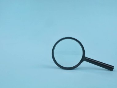 Açık mavi arka planda siyah büyüteç. Arama, keşif, soruşturma, araştırma, denetim ve çözüm bulma kavramları için mükemmel.