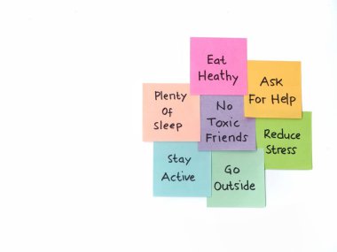 Sağlıklı bir yaşam tarzı ve zihinsel refah için el yazısıyla yazılmış ipuçları beyaz arka plan üzerine renkli yapıştırıcı kağıt üzerinde