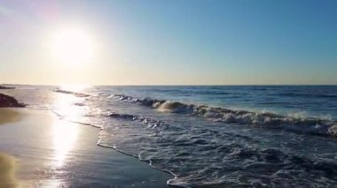 Sakin mavi okyanus dalgaları ve berrak ufukta ilerleyen kamera parlak güneş ışığıyla mavi deniz dalgalarına doğru ilerliyor. Yüksek kalite 4k görüntü