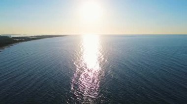 Mavi deniz kıyısı ve insansız hava aracından görünen parlak güneş drone 'dan görünen sahile ulaşan sakin deniz dalgaları. Yüksek kalite 4k görüntü