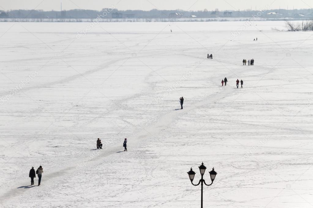 People walk on the river ice in winter