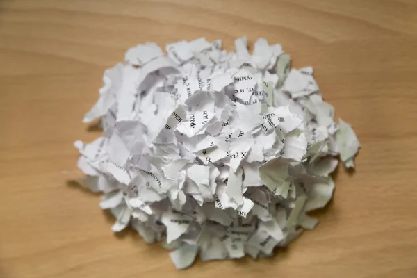A pile of torn paper with text on wooden table — Stock Photo, Image