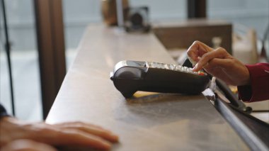 Müşteri otel resepsiyonunda kredi kartı terminalini kullanarak ödeme yapıyor, işlem sürecini kapatıyor