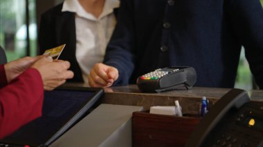 Müşteri otel resepsiyonunda kredi kartı terminalini kullanarak ödeme yapıyor, işlem sürecini kapatıyor