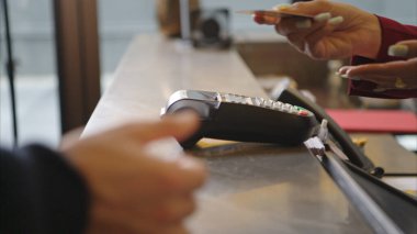 Müşteri otel resepsiyonunda kredi kartı terminalini kullanarak ödeme yapıyor, işlem sürecini kapatıyor