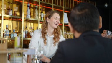 Modern bir barda müşterilere içki servisi yapan gülümseyen barmen.