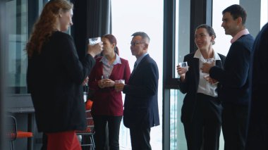 Modern bir ofis ortamındaki kurumsal bir etkinlikte iş dünyasından profesyoneller içki içip eğleniyorlar.