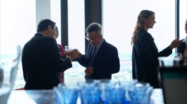 Modern bir ofis ortamındaki kurumsal bir etkinlikte iş dünyasından profesyoneller içki içip eğleniyorlar.