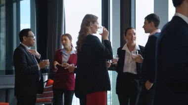 Modern bir ofis ortamındaki kurumsal bir etkinlikte iş dünyasından profesyoneller içki içip eğleniyorlar.