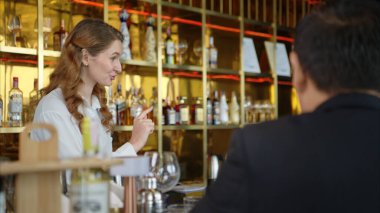 Modern bir barda müşterilere içki servisi yapan gülümseyen barmen.