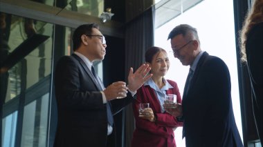 Modern bir ofis ortamındaki kurumsal bir etkinlikte iş dünyasından profesyoneller içki içip eğleniyorlar.