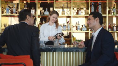 Modern bir barda müşterilere içki servisi yapan gülümseyen barmen.