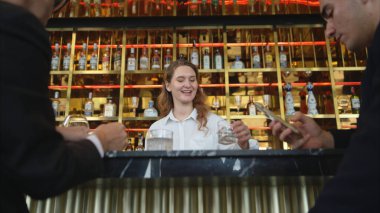 Modern bir barda müşterilere içki servisi yapan gülümseyen barmen.