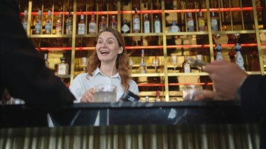 Modern bir barda müşterilere içki servisi yapan gülümseyen barmen.