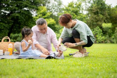 Mutlu Asyalı nesiller parkta pikniğin tadını çıkararak neşeli bir açık hava yaşam tarzı yaratıyor.