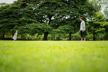 Baba ve kızı parkta pikniğin tadını çıkarıyorlar, neşeli bir açık hava yaşam tarzı yaratıyorlar.